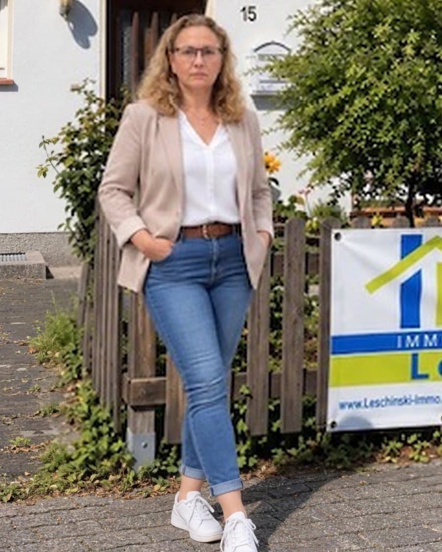 Daniela Leschinski vor einem Haus mit ihrem Schild „Zu verkaufen“