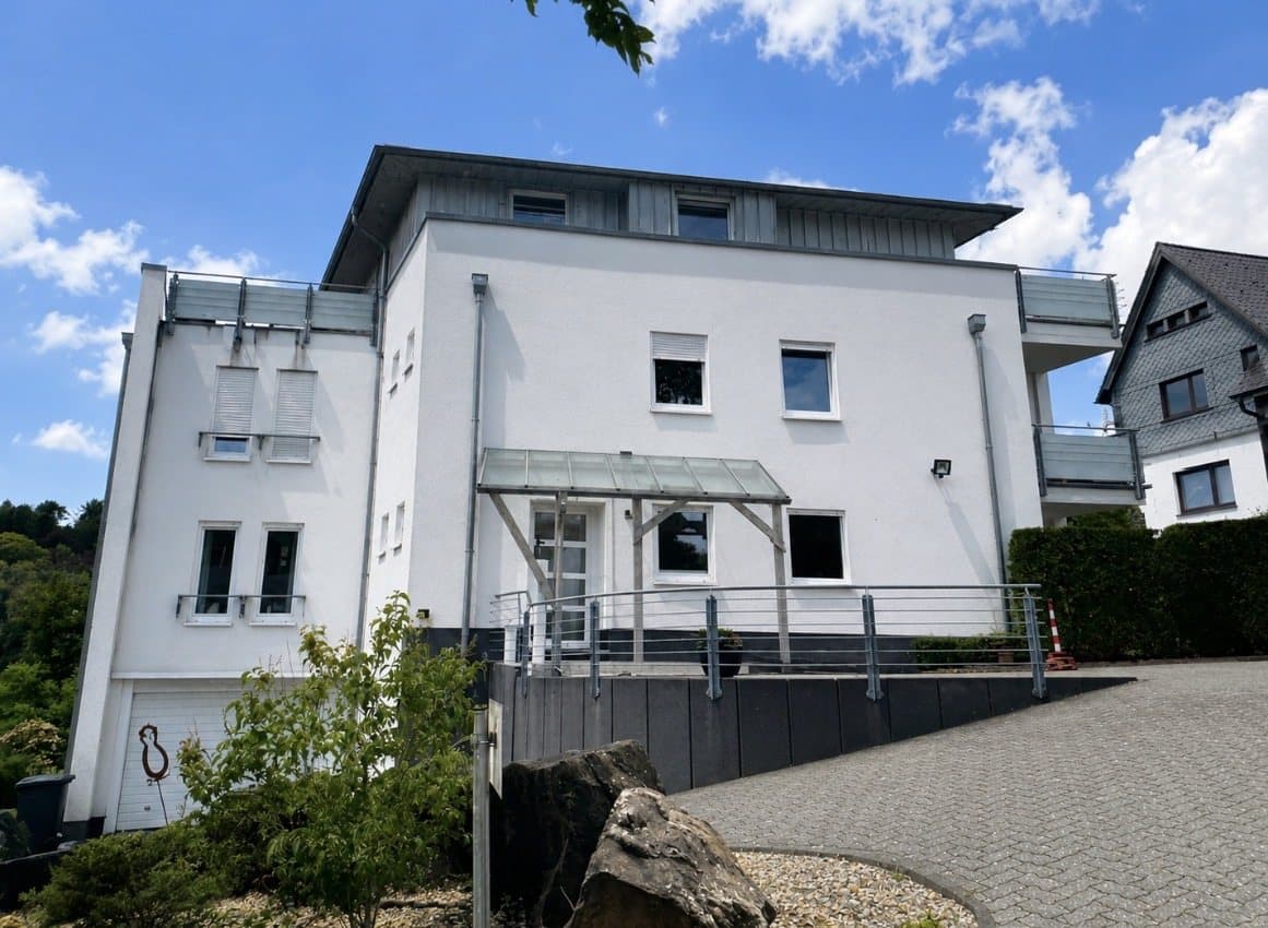 Weißes Wohnhaus mit Glasvordach am Hang, daran sechs Punkte, die in eine Bewertung einfließen